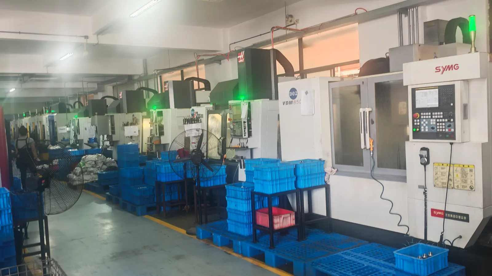 GUTUBAO CNC machining shop floor with rows of machining centers and blue part bins, where sprayer pump components are machined.